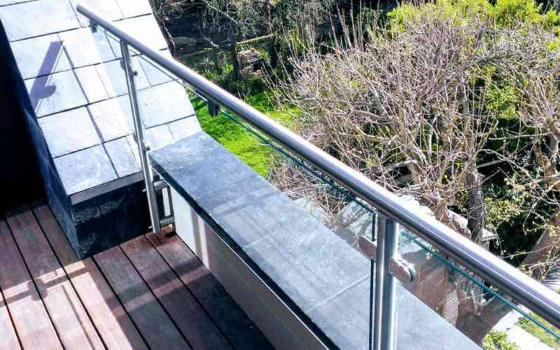 Parapet wall with glass balustrade top rail